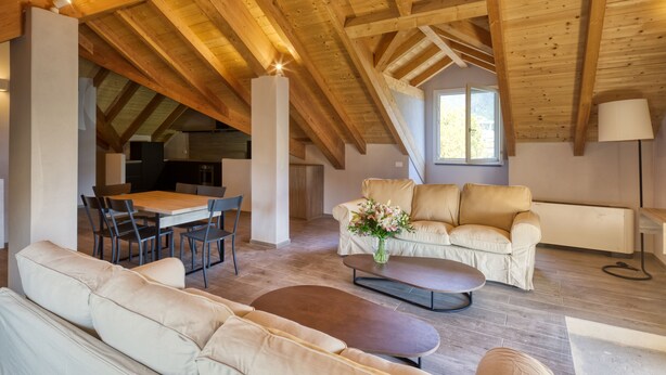 Un loft spacieux avec de hauts plafonds, un coin repas, un salon avec un canapé et une table basse, et une cuisine à l’arrière-plan.