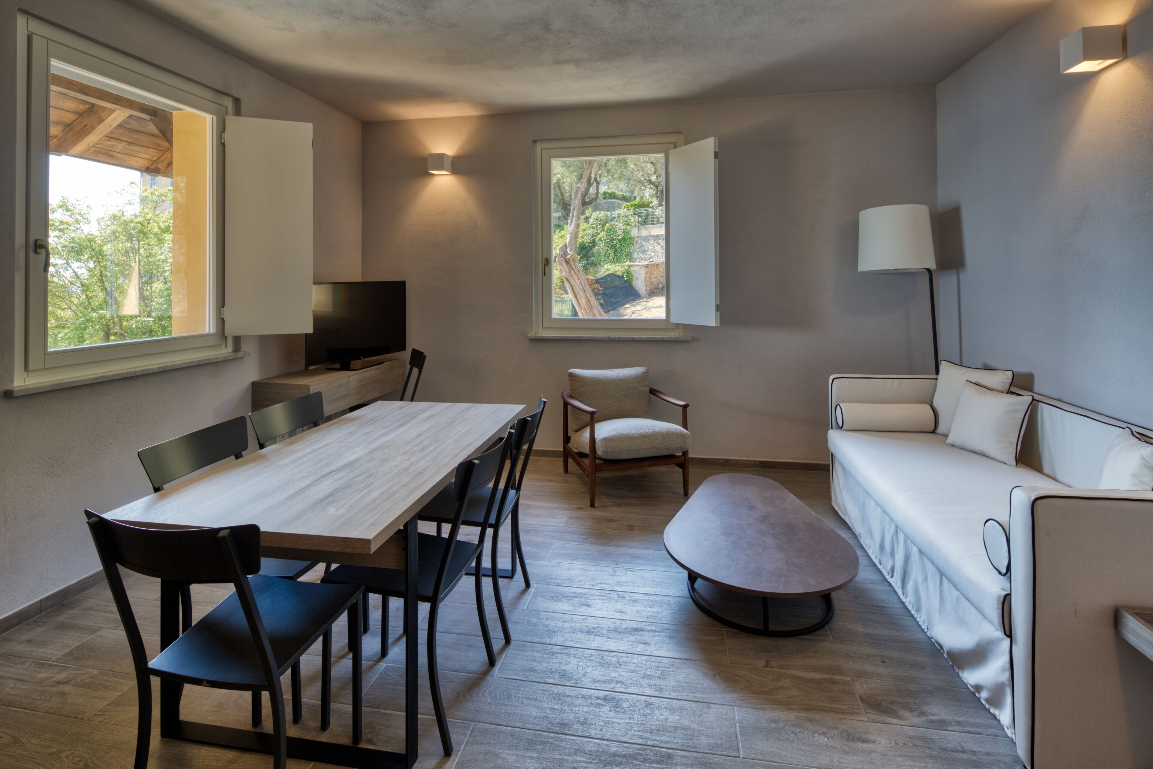 A compact living space with a dining table, chairs, a sofa, and a TV.