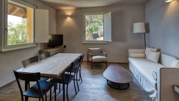 Un espacio habitable compacto con una mesa de comedor, sillas, un sofá y un televisor.