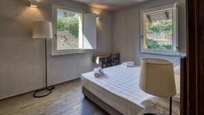 Une chambre à coucher avec un lit, des lampes de chevet, un bureau et deux fenêtres.