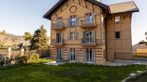 Un immeuble à plusieurs étages doté de balcons, d’un jardin et surplombant un paysage montagneux.