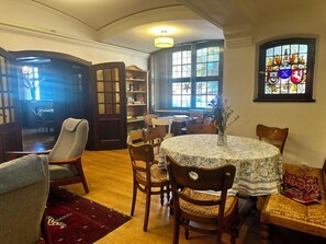 A cozy dining area with a round table, wooden chairs, and a stained glass window.