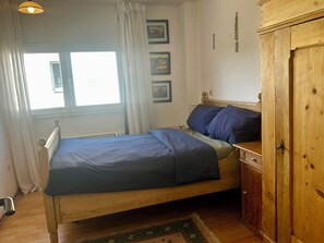 A single bed with a wooden headboard, a bedside table, and a wardrobe.