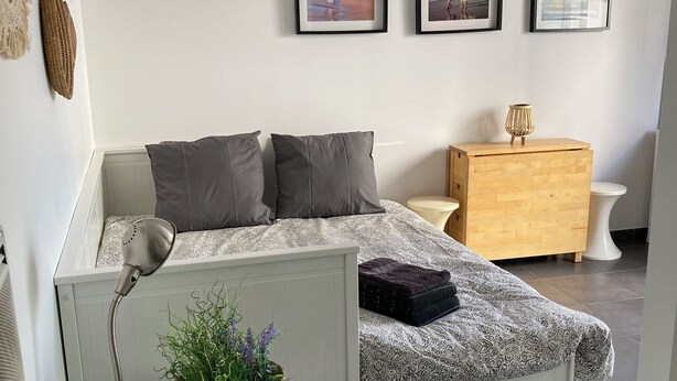 A modern bedroom with a bed, bedside table, lamp, and a small potted plant. - Appartement Avec Terrasse et Parking à Anglet (Anglet)