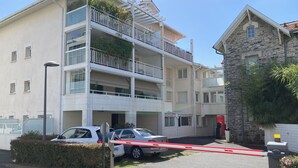 A multi-story residential building with balconies, a gated parking area, and a stone building adjacent to it. - Appartement Avec Terrasse et Parking à Anglet (Anglet)