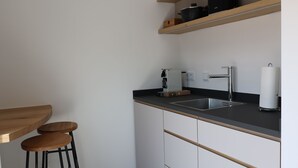 Una cocina moderna con dos lavamanos de acero inoxidable, taburetes de bar de madera y una encimera negra.