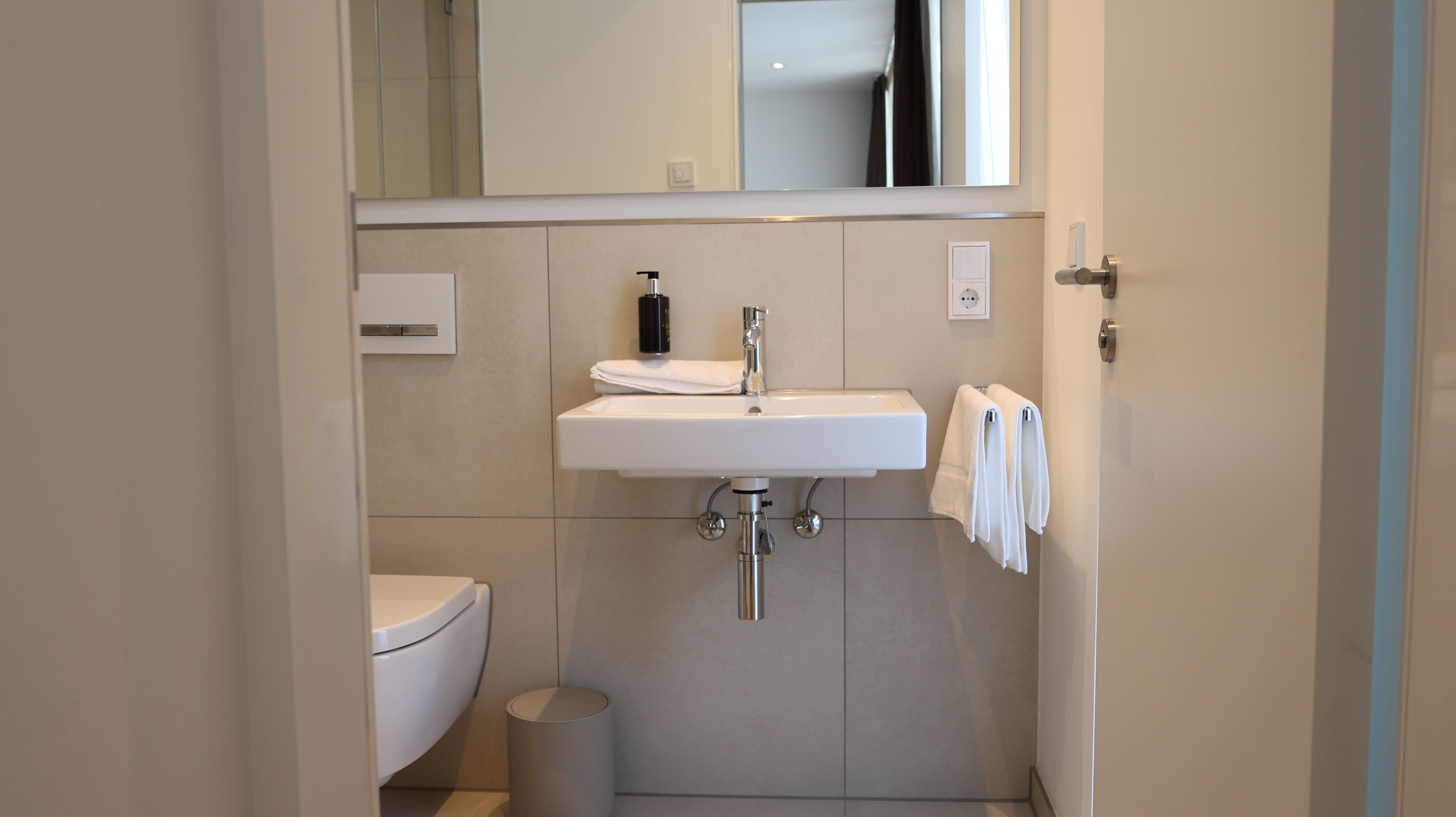 Ein kleines Badezimmer mit Waschbecken, Toilette und Spiegel über dem Waschbecken.