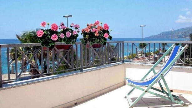Ein Balkon mit Meerblick, einem Stuhl und Topfpflanzen.