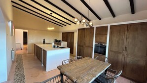 Een moderne keuken met een centraal eiland, een houten eettafel en inbouwmeubels.