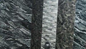 A shower with dark, textured walls and a stone-patterned floor. - Alona Beach Poolside Hotel (Panglao)