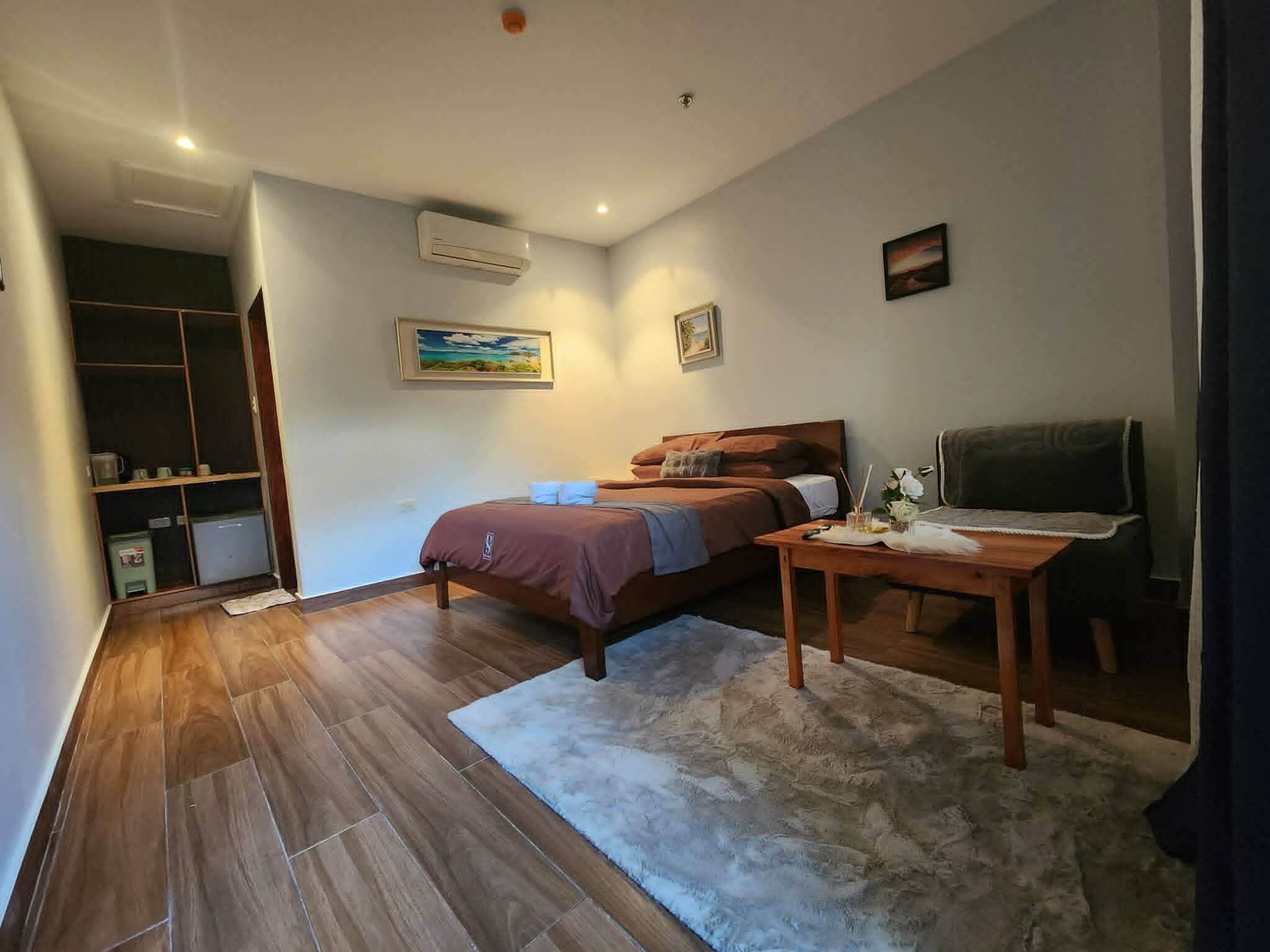 Ein Schlafzimmer mit Bett, Schreibtisch, Stuhl, Kleiderschrank und einem Bild an der Wand.