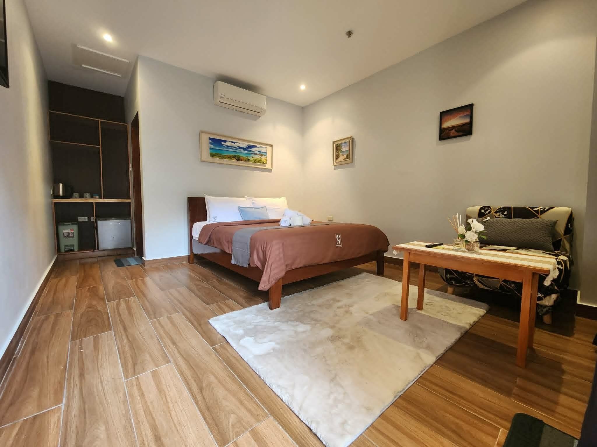 Een slaapkamer met een bed, een nachtkastje, een stoel, een kledingkast en een tafeltje met een bloevas.