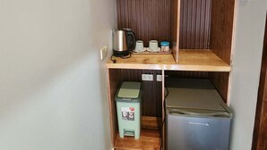 A compact kitchenette with a wooden countertop, a kettle, a coffee maker, and a small refrigerator. - Alona Beach Poolside Hotel (Panglao)
