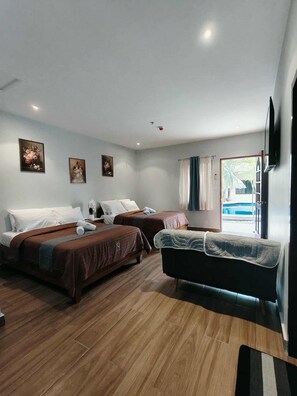 Ein Hotelzimmer mit zwei Betten, einer Couch, einem Flachbildfernseher und Bildern an den Wänden.