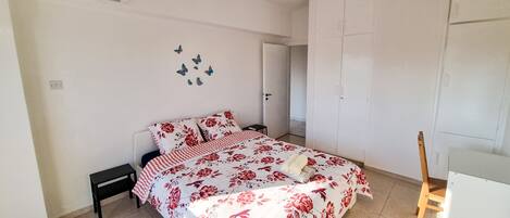 A bedroom with a bed, a nightstand, a wardrobe, and an air conditioning unit.