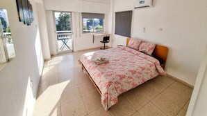 A bedroom with a bed, a desk, and a balcony. - City View Rooms (Larnaca)