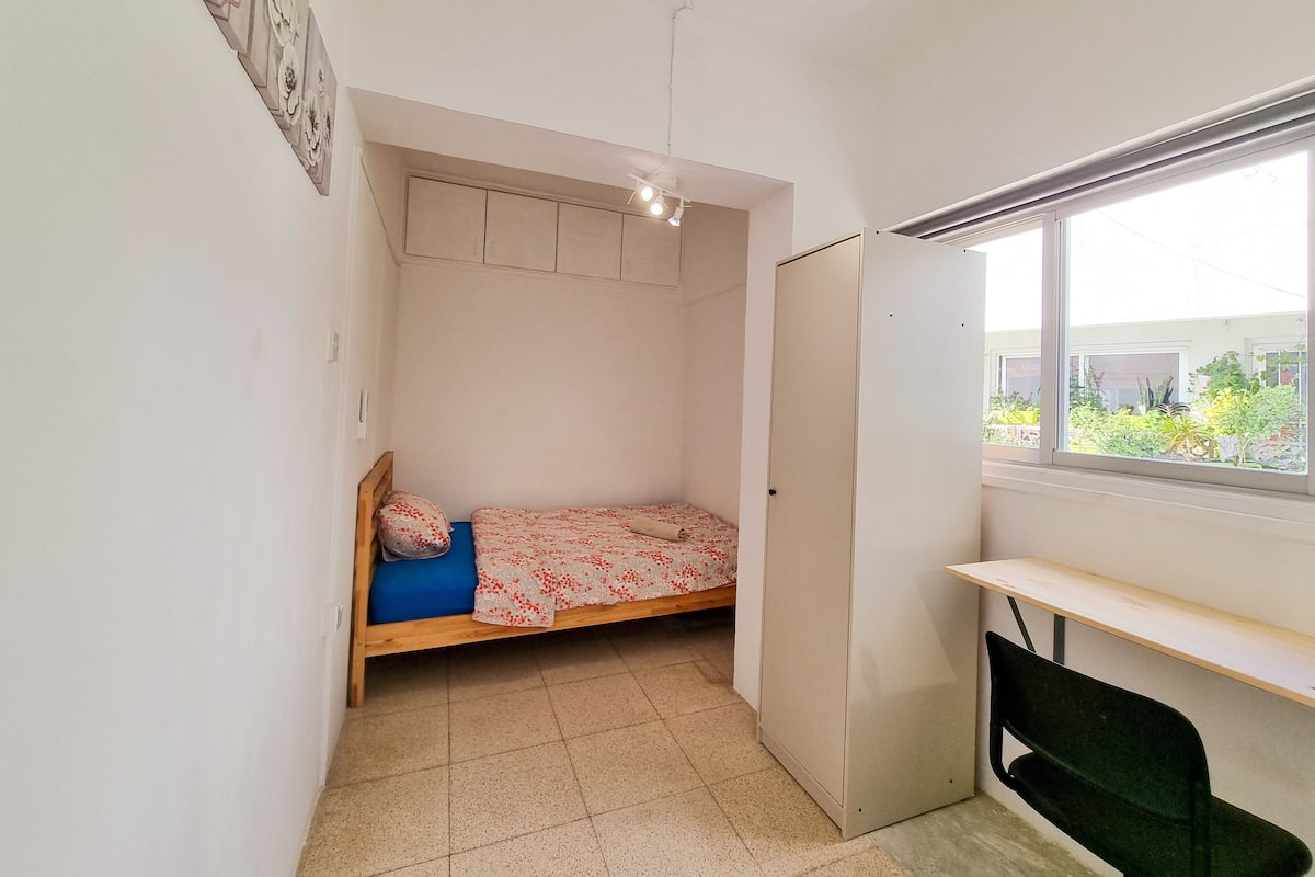 A small, single-bed room with a desk and a window.