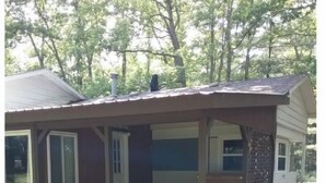 A small cabin with a porch, a chimney, and a window. - Summer fun in the Huron National Forest just minutes from the Au Sable River. (Glennie)