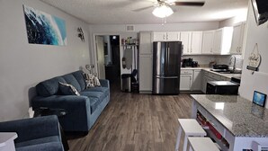 Una cocina moderna con armarios blancos, un refrigerador negro y piso de madera.