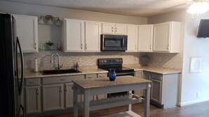 Una cocina moderna con gabinetes blancos, un refrigerador de acero inoxidable, un microondas y una estufa.