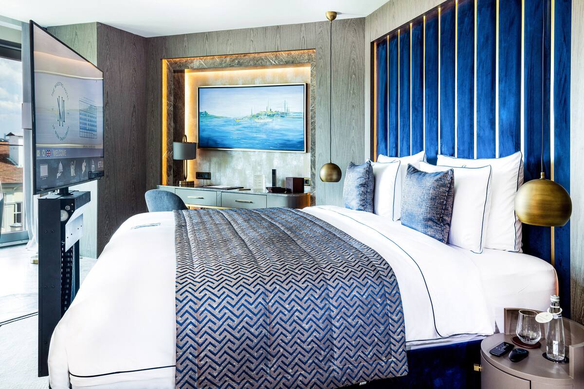 A modern hotel room with a large bed, a desk, and a TV.