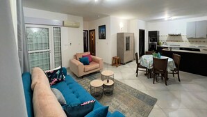 A living room with a sofa, a small table, and a dining area with chairs and a table. - Appartements - Le Paradisier Ambatobe (Antananarivo)
