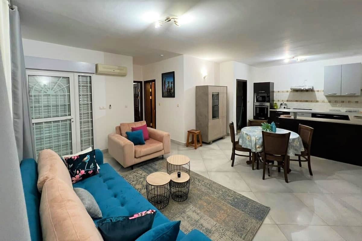 A living room with a sofa, a small table, and a dining area with chairs and a table.