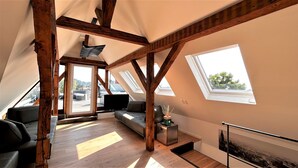 Un apartamento estilo loft con vigas de madera a la vista, un sofá, un televisor de pantalla plana y una chimenea.
