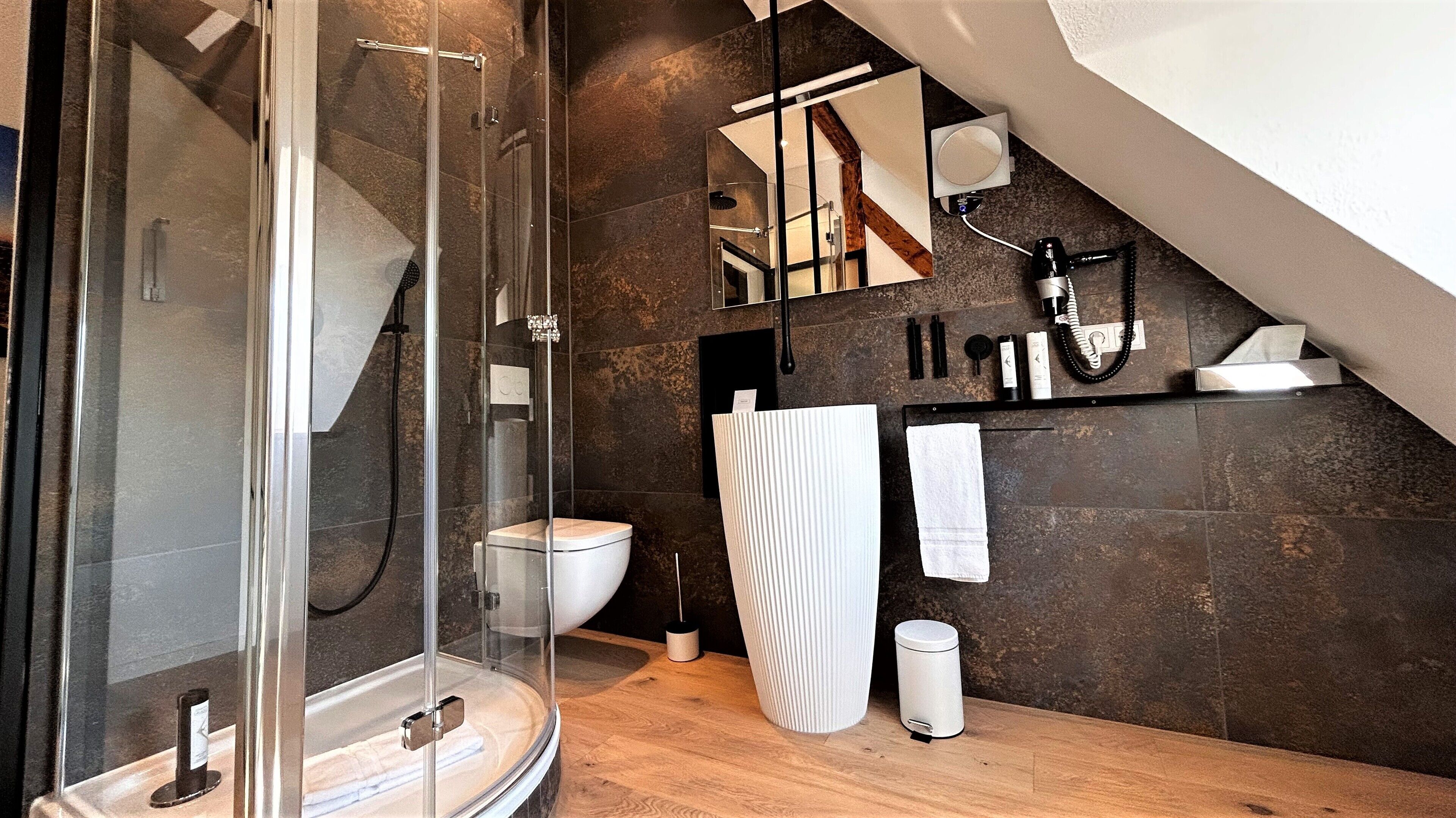 Une salle de bain moderne dotée d’une douche à parois de verre, de toilettes et d’un espace lavabo.