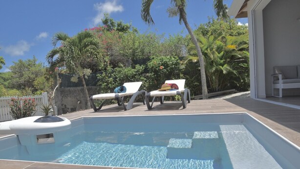 Une piscine avec deux chaises longues et un petit espace aménagé autour.