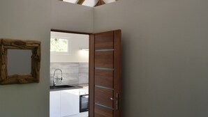 Une pièce avec un plafond en pente, une porte en bois et une vue sur un espace cuisine.