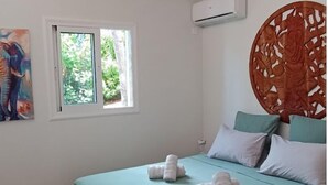 Une chambre à coucher avec un lit, un ventilateur de plafond, une fenêtre et un tableau.