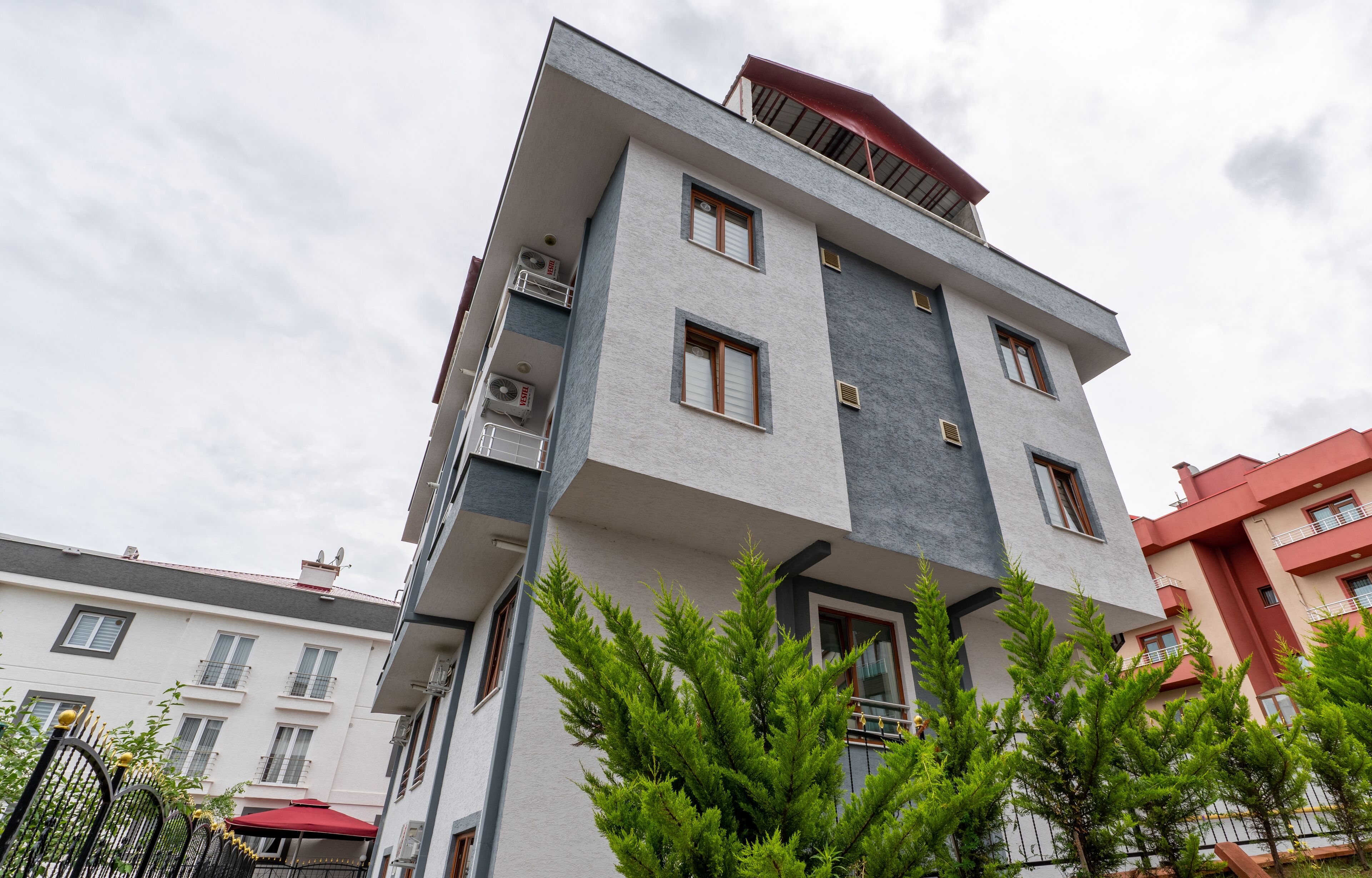 A multi-story building with balconies, air conditioning units, and a red awning.