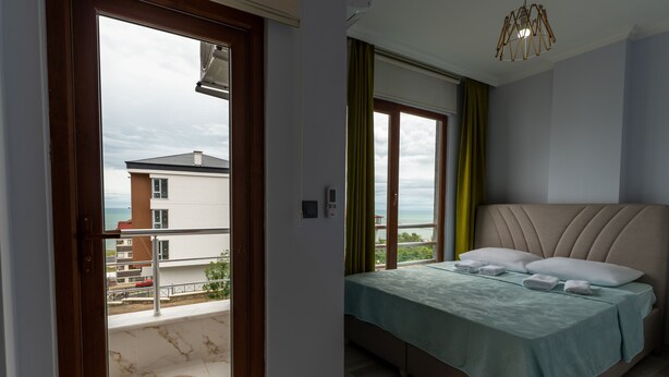 Un dormitorio con cama, balcón y vista a edificios.