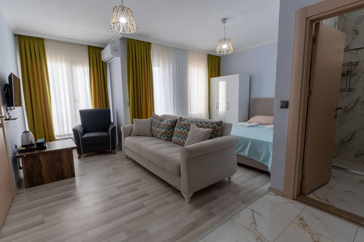 Una sala moderna con sofá, sillón y cama. Hay una mesa de centro de madera, un televisor y un armario.