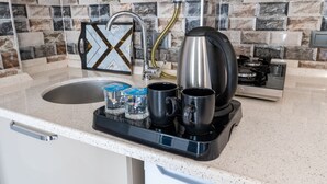 Una cocina de diseño moderno, con un lavamanos de acero inoxidable, una cafetera y una bandeja con dos tazas y una botella de agua.