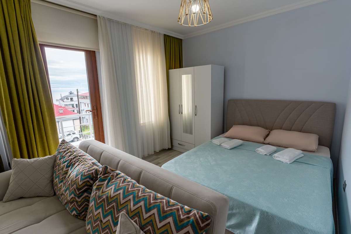 Un dormitorio con cama, armario, sofá y vistas a edificios.