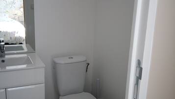 A small, clean bathroom with a toilet, sink, and cabinet.