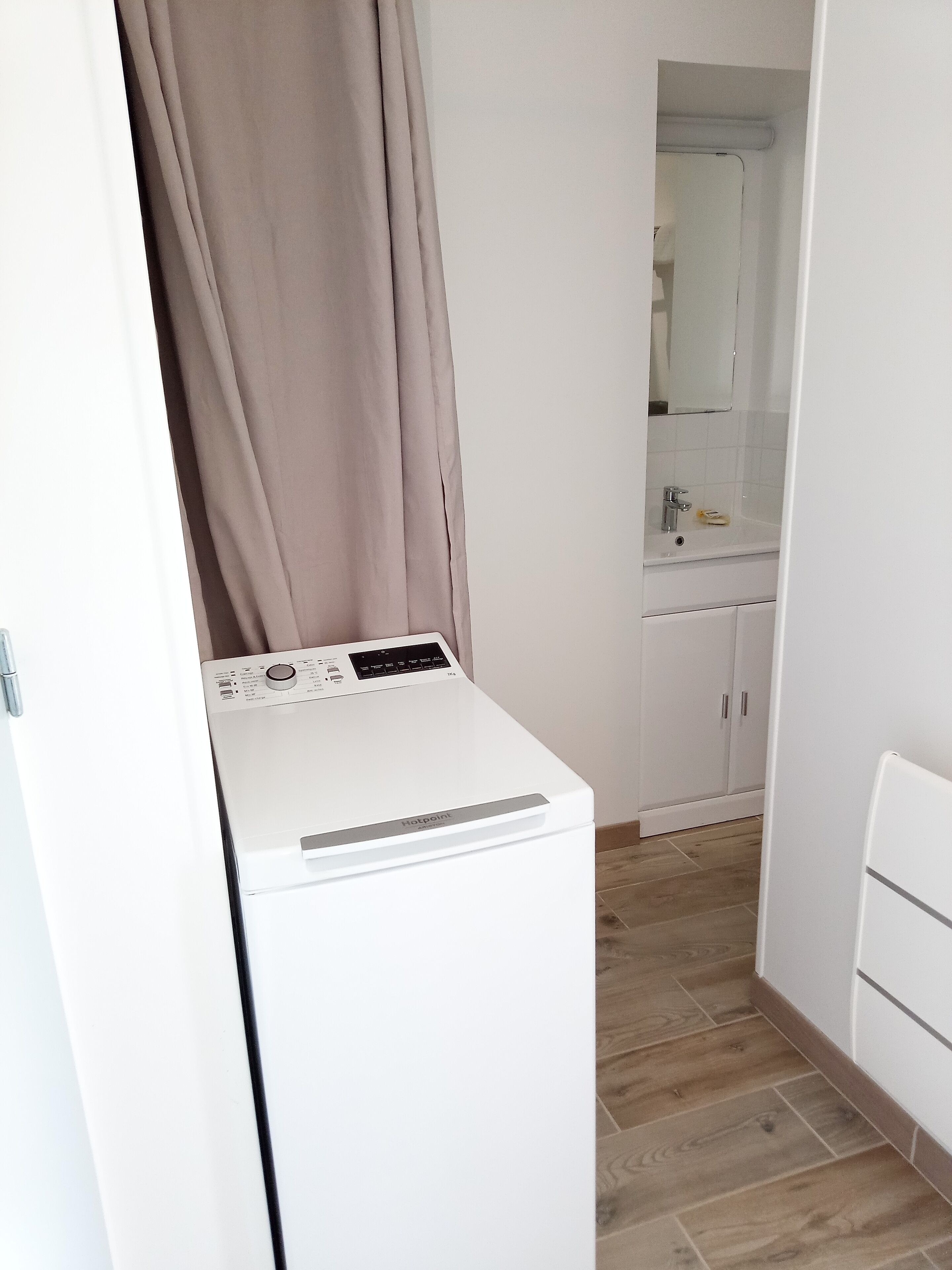 A compact laundry area with a washing machine, a sink, and a mirror.