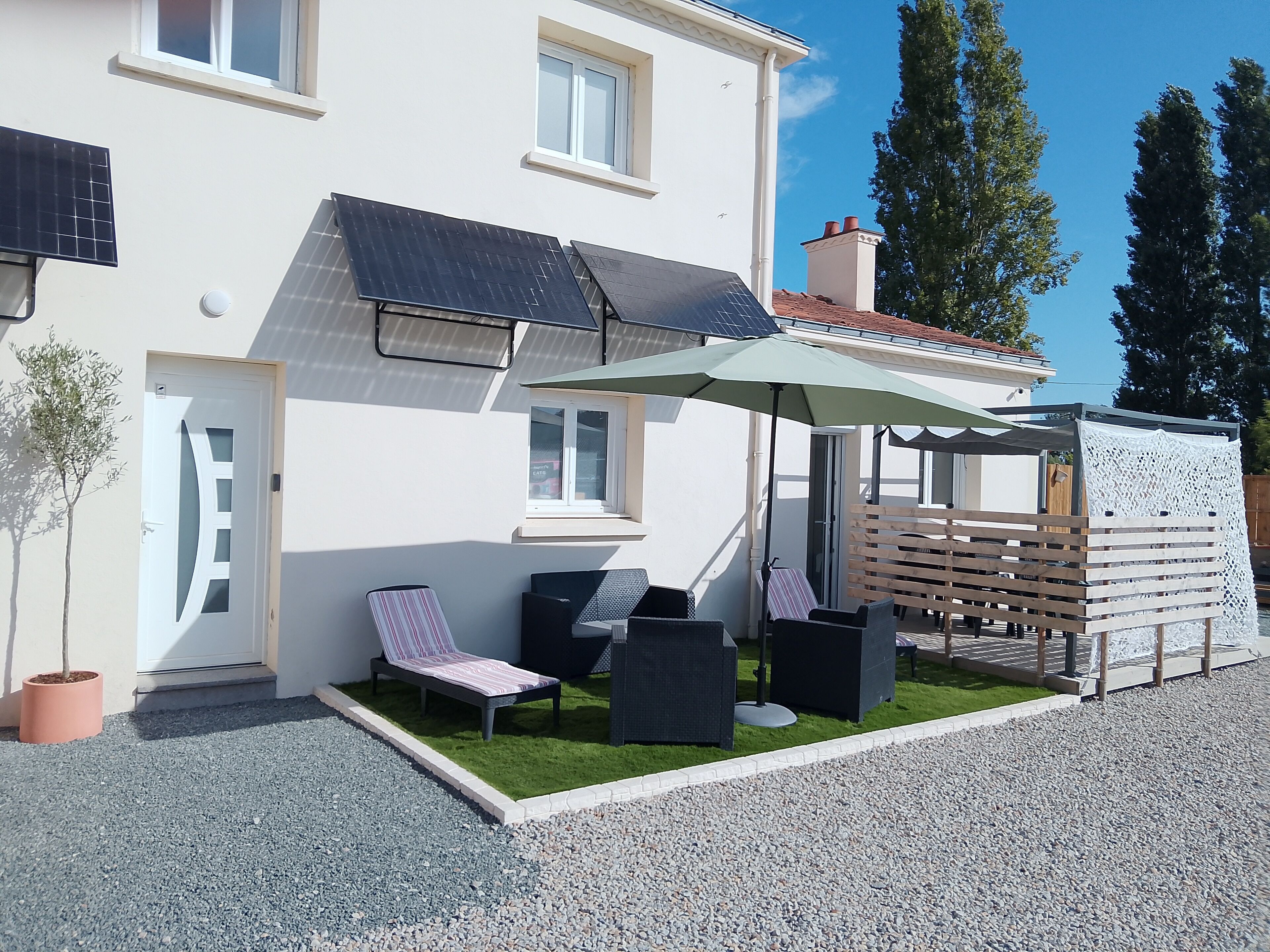 A modern house with a covered patio, solar panels, and a small garden.