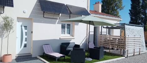 A modern house with a covered patio, solar panels, and a small garden.