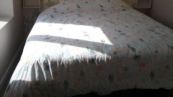 Ein Schlafzimmer mit einem blumengemusterten Kopfteil, einem Bett mit farbenfroher Blumenbettdecke und zwei Nachttischlampen.