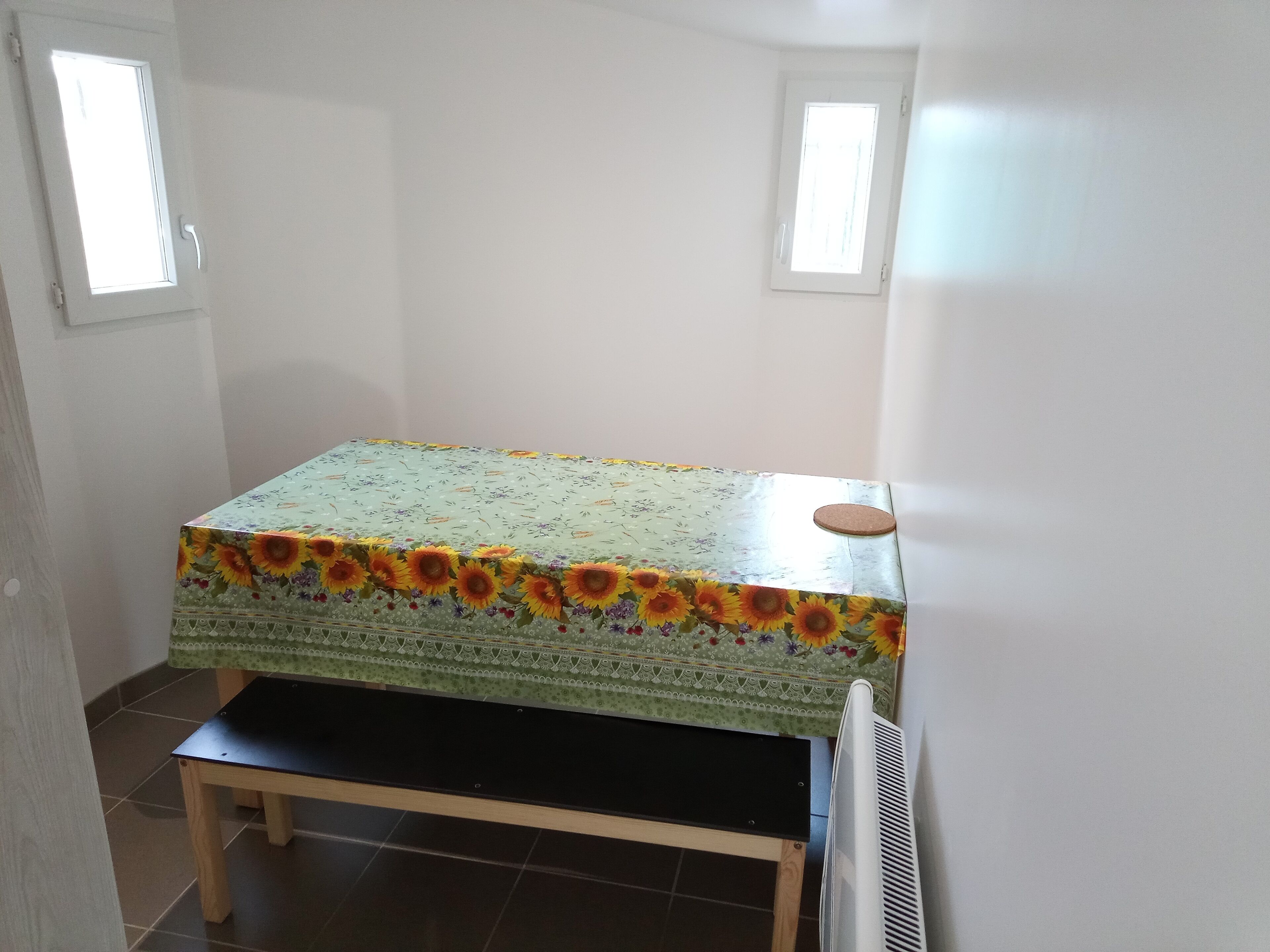 Una habitación pequeña con una cama, una mesa y dos ventanas.