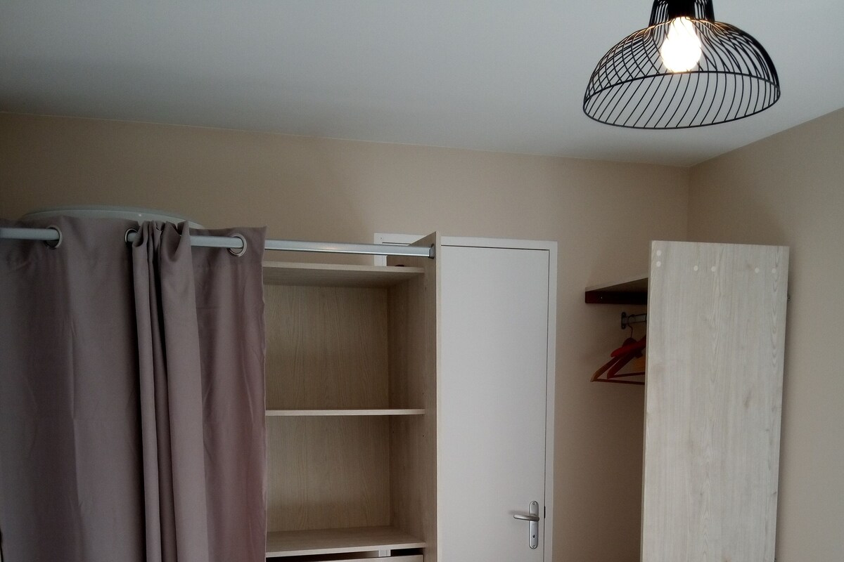 A bedroom with a bed, a wardrobe, and a closet with shelves.