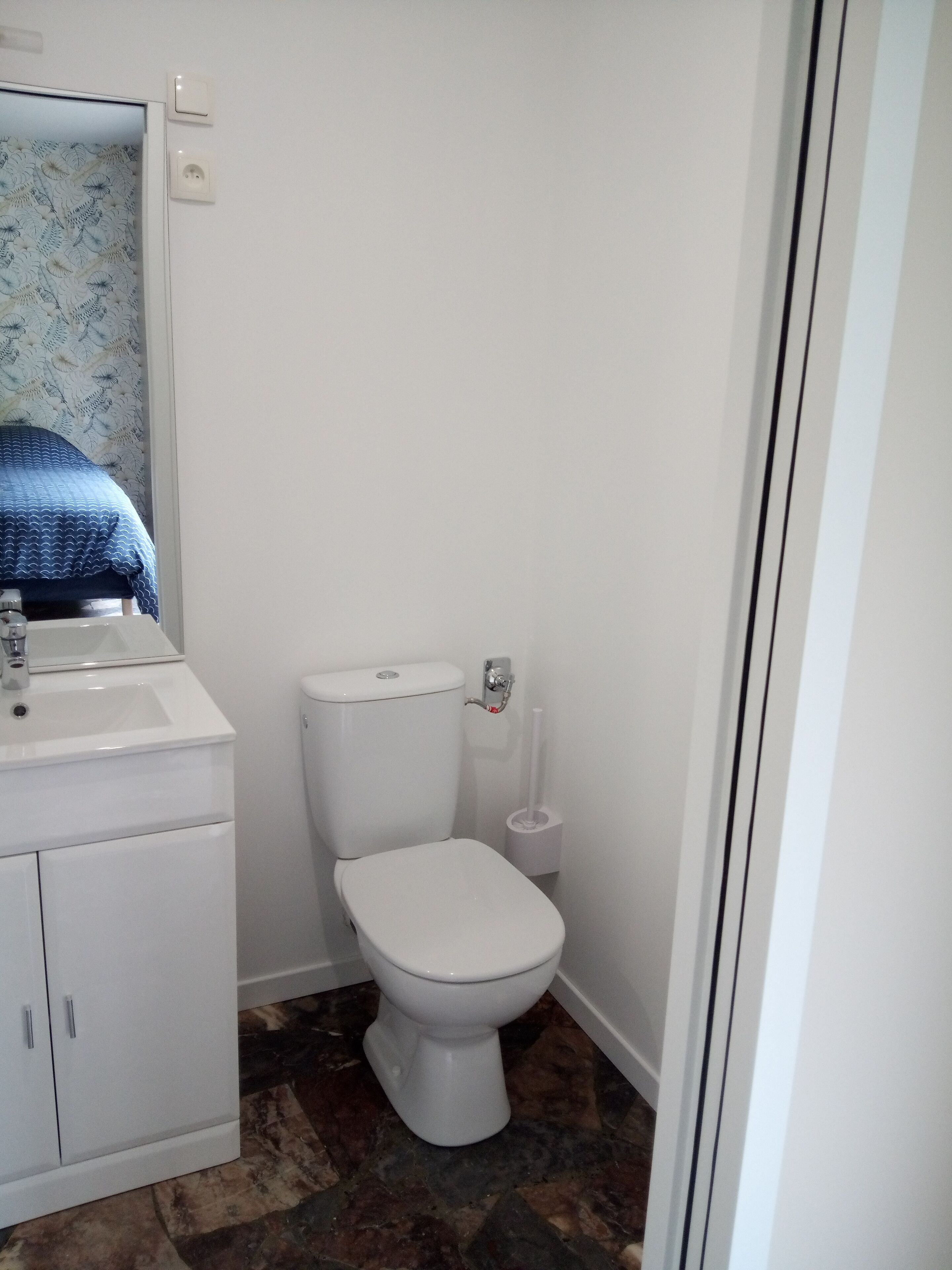 A small, clean bathroom with a white toilet, a sink, and a mirror.