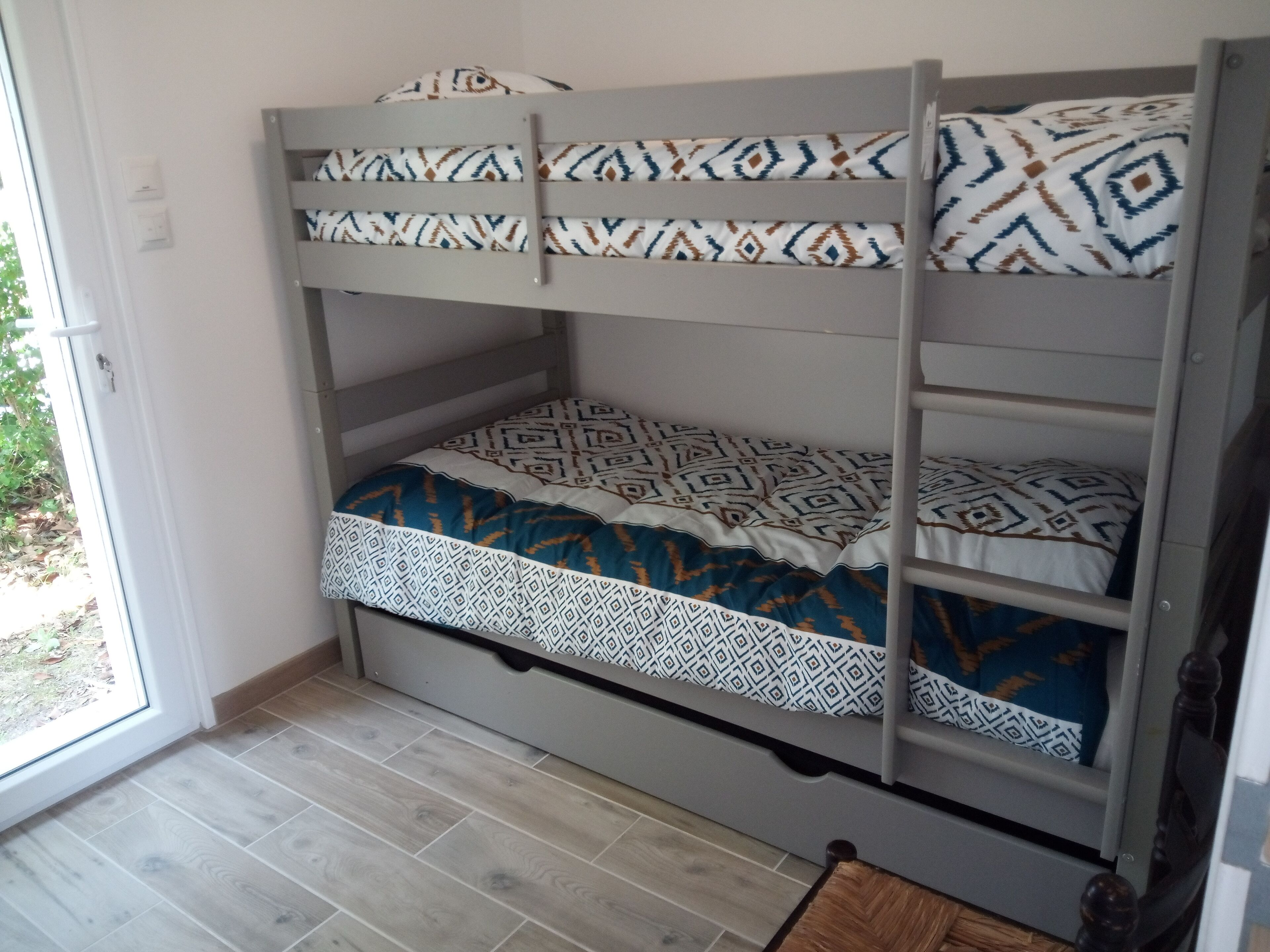 A bunk bed with patterned bedding and a wooden floor.