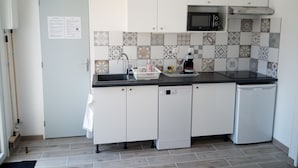 A compact kitchen with white cabinets, a black countertop, a microwave, and a dishwasher.