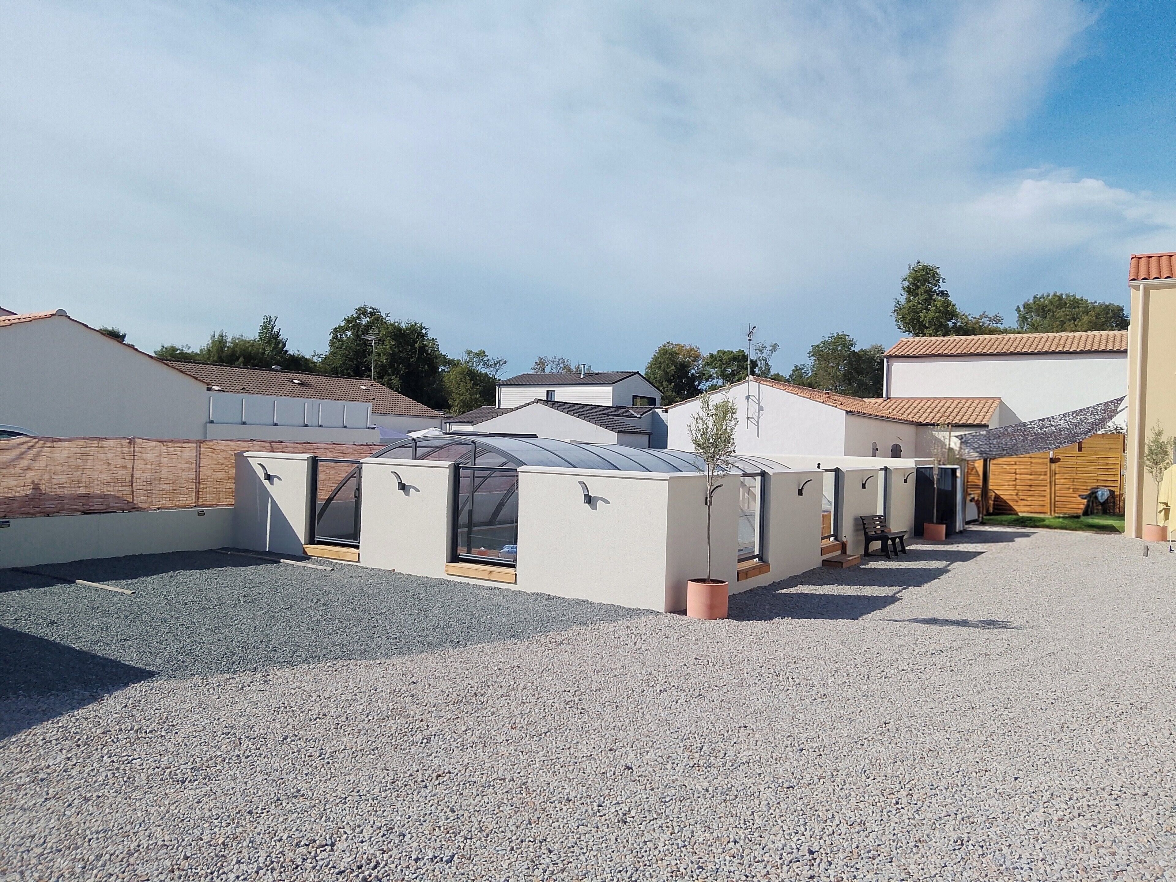 A residential area with multiple houses, a gravel driveway, and a clear sky.