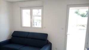 A room with a dark blue sofa, a window, and a door leading outside.
