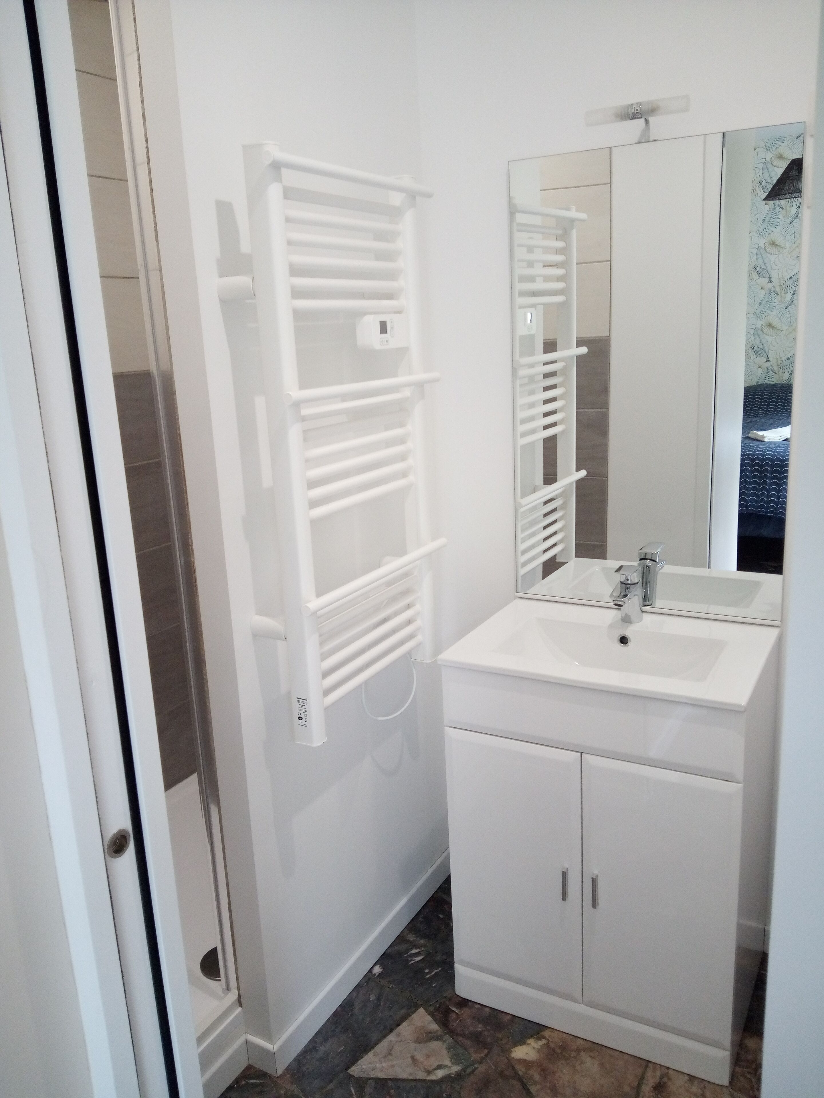 A bathroom with a white sink, mirror, and towel rack.